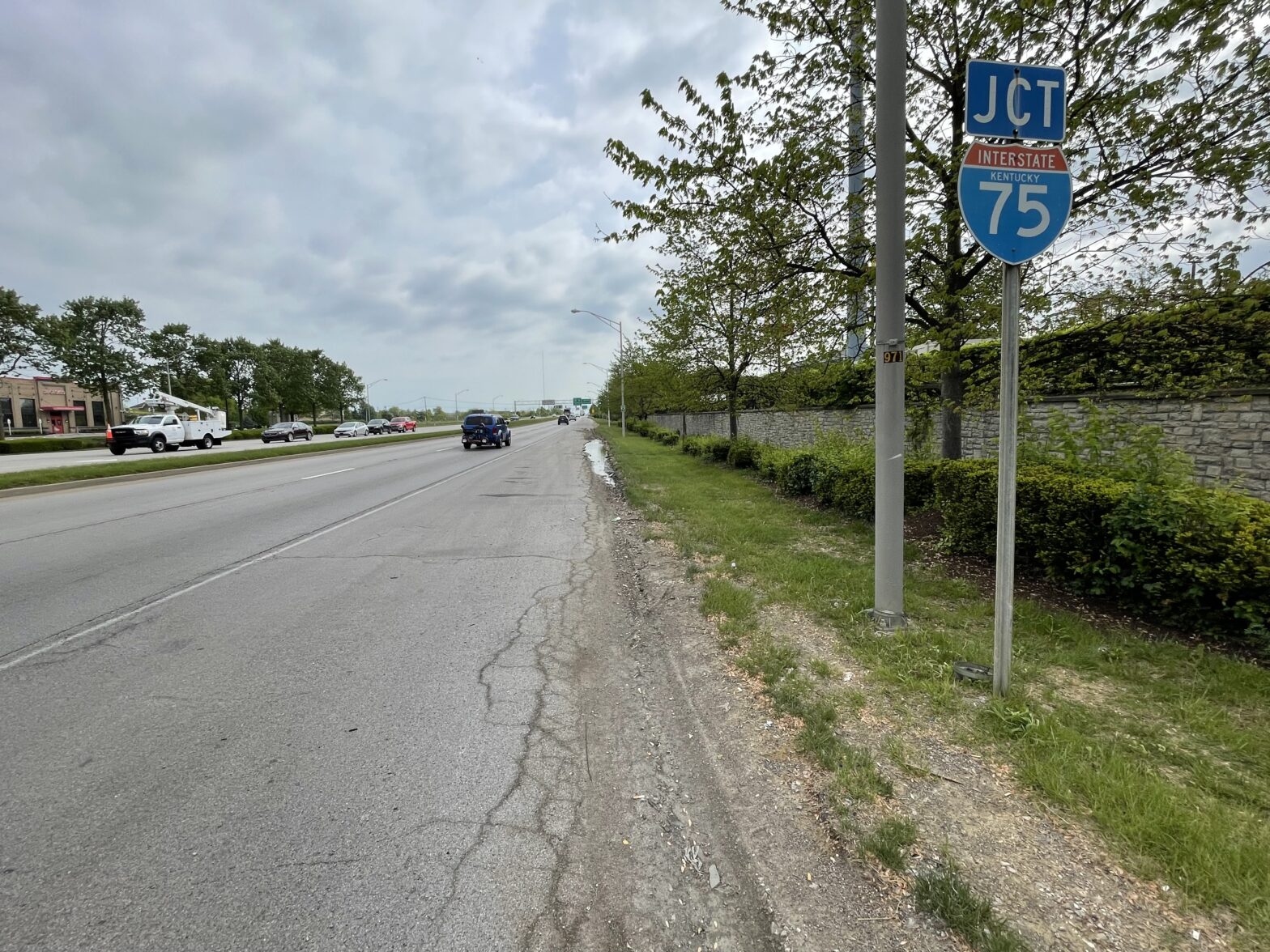 New temporary bus stop location shown on the same road, slightly before the current stop, positioned away from the road damage and water accumulation for improved safety and accessibility.